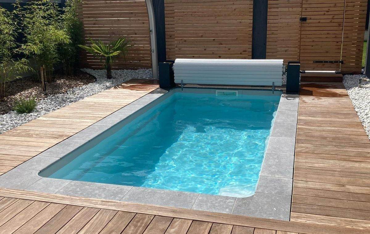 Piscine coque polyester avec terrasse bois et volet immergé
